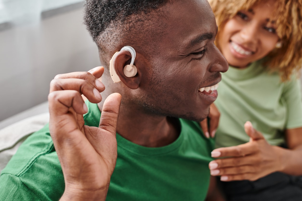 Man trying on his new hearing aid with his girlfriend