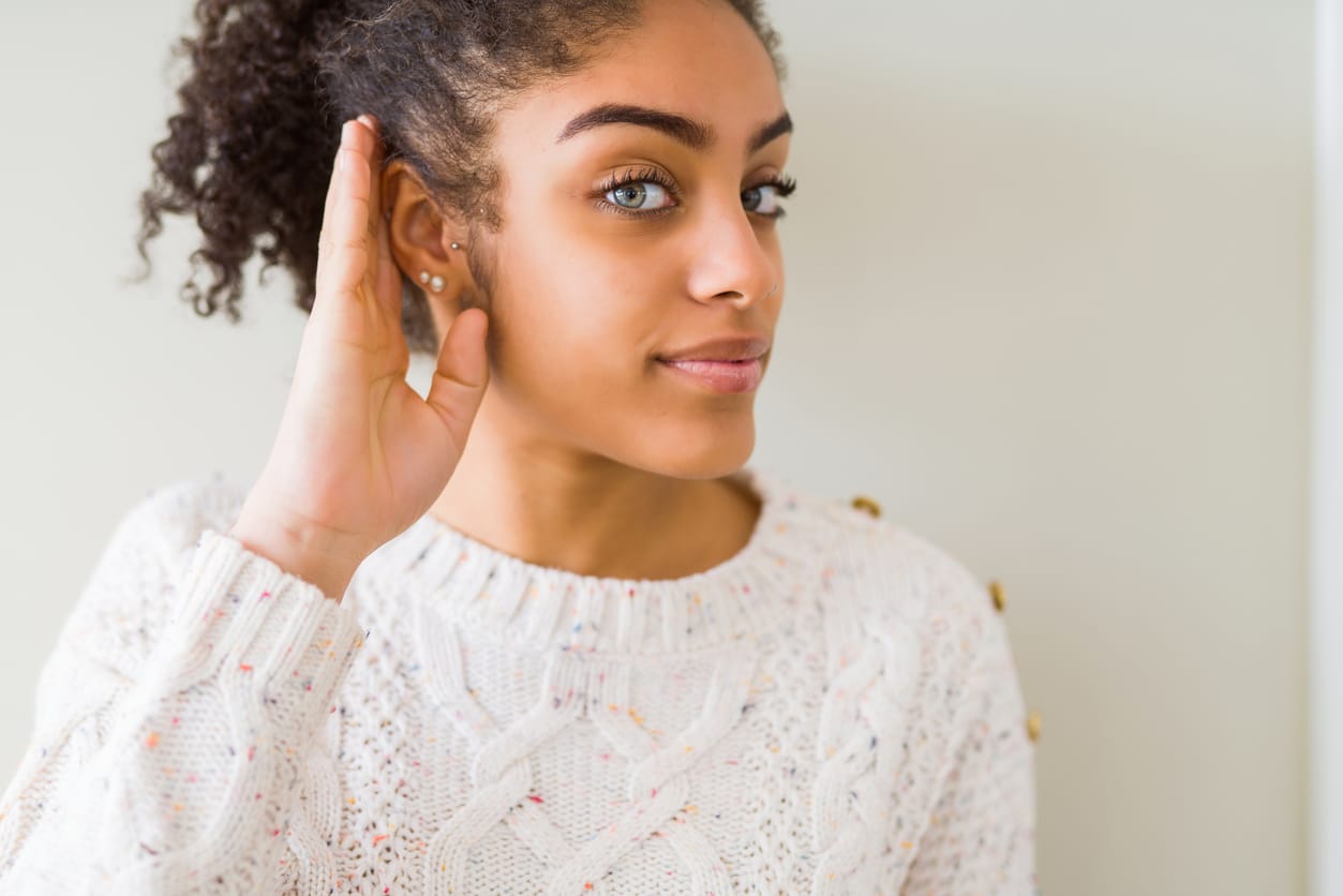 Smiling woman holding her hand to her ear