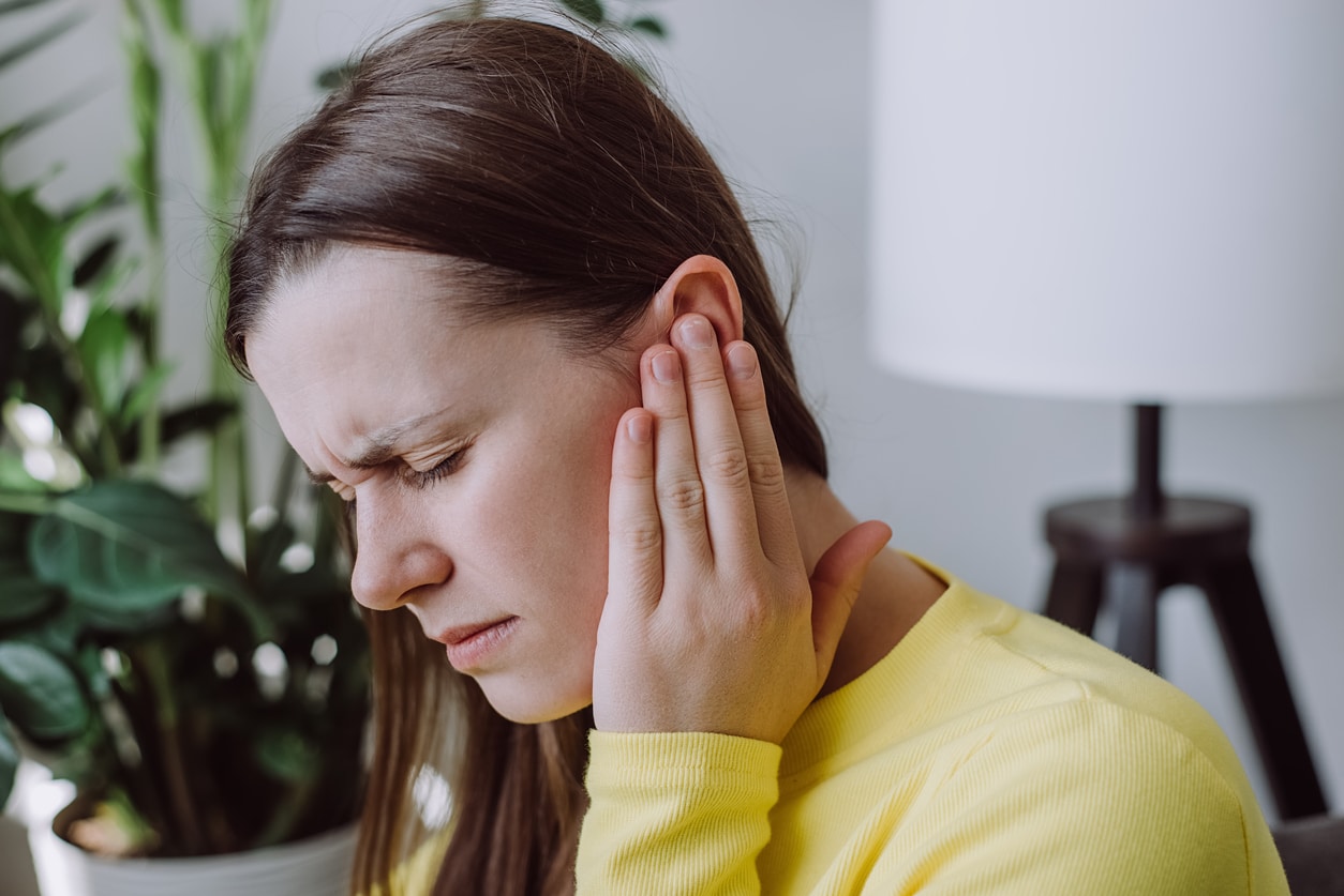 Woman holding her ear, trying to block tinnitus